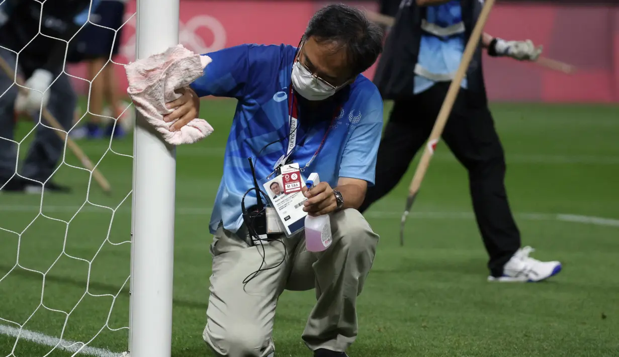 Petugas mendisinfeksi tiang gawang untuk menghentikan penyebaran virus corona COVID-19 setelah pertandingan sepak bola putaran pertama grup C putra Olimpiade Tokyo 2020 antara Mesir dan Spanyol di Sapporo Dome, Sapporo, Jepang, Kamis (22/7/2021). (ASANO IKKO/AFP)