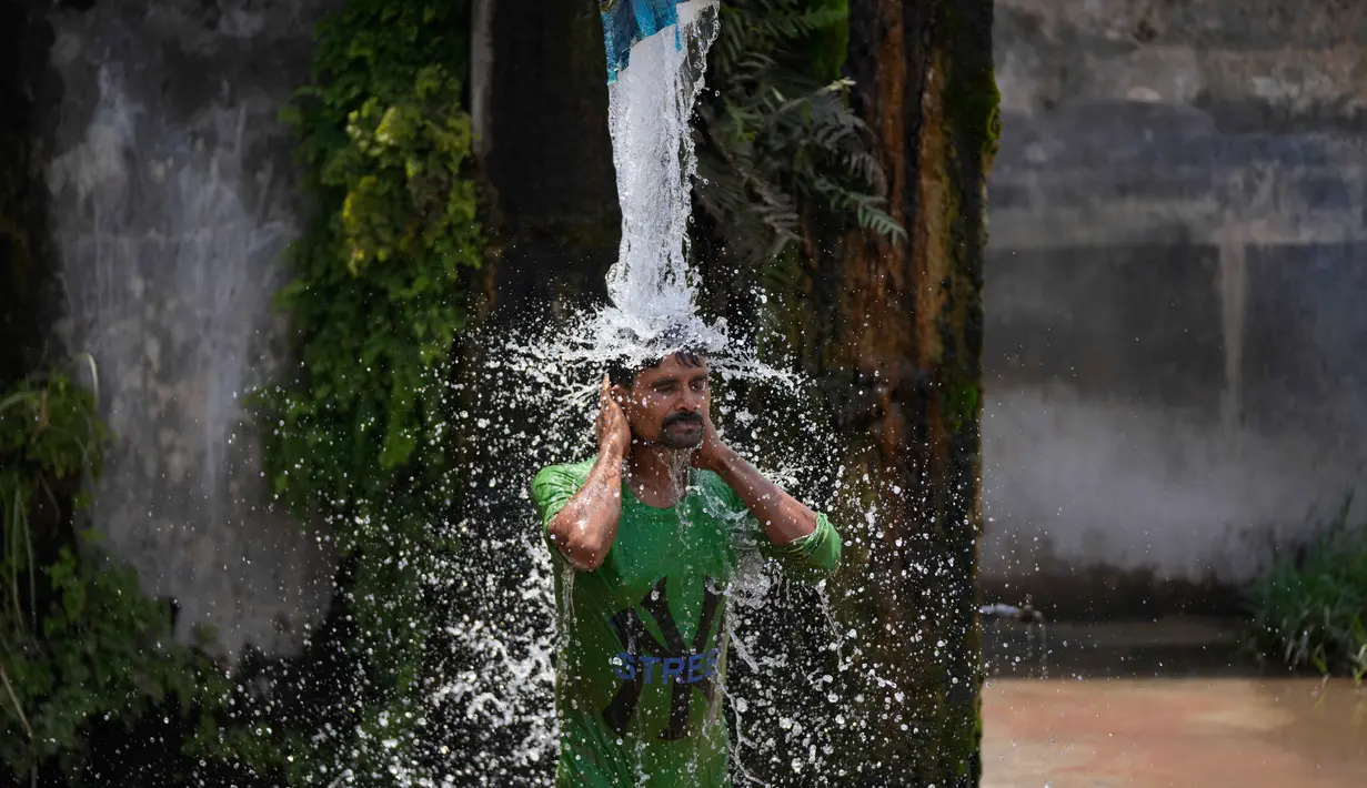 Seorang pria mandi menggunakan keran air pinggir jalan untuk mendinginkan diri di hari yang panas di pinggiran Jammu, India, Selasa 19 Mei 2026. (AP Photo/Channi Anand)