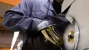 Pekerja membersihkan bagian body alat musik saksofon di pabrik Selmer Saxophone di Mantes-la-Ville, Prancis (17/1). Saksofon biasanya terbuat dari logam dan dimainkan menggunakan single-reed seperti klarinet. Saksofon. (AFP Photo/Alain Jocard)