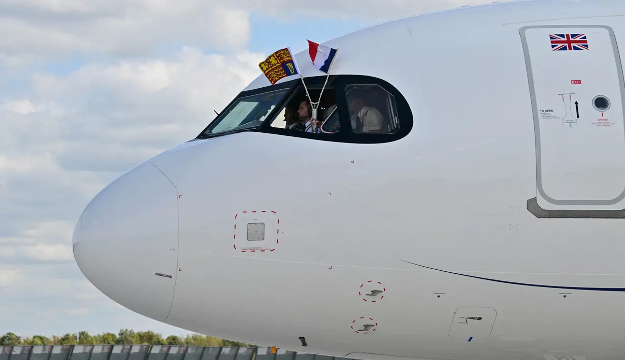 Pilot mengibarkan bendera Kerajaan Inggris dan Prancis dari kokpit pesawat yang mengangkut Raja Inggris Charles III dan Ratu Inggris Camilla saat mendarat di Bandara Orly pada 20 September 2023. (Miguel MEDINA/POOL/AFP)