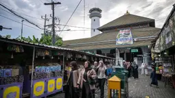 Sore menjelang waktu berbuka, kawasan ini ramai dikunjungi warga dan sejumlah pedagang pakaian/makanan beroperasi hingga 24 jam. Tampak dalam foto, warga berjalan saat bulan suci Ramadan di sekitar Masjid Sunan Ampel, Surabaya, Jawa Timur, pada Minggu 8 Maret 2026. (JUNI KRISWANTO/AFP)