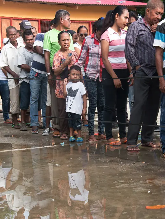 Seorang anak terlihat dalam antrean warga Timor Leste yang akan menggunakan hak pilih mereka di tempat pemungutan suara (TPS) yang berada di Dili, Senin (20/3). Sedikitnya 1,2 juta warga akan memilih presiden baru Timor Leste. (Valentino DARIEL SOUSA/AFP)