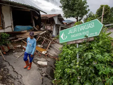 Seorang pria berjalan di samping rumah-rumah yang rusak setelah pergerakan tanah melanda permukiman mereka di desa Padasari, Tegal, Jawa Tengah, Senin 9 Februari 2026. Fenomena tanah bergerak di Desa Padasari, Kecamatan Jatinegara, Kabupaten Tegal, Jawa Tengah masih terus terjadi. (DEVI RAHMAN/AFP)