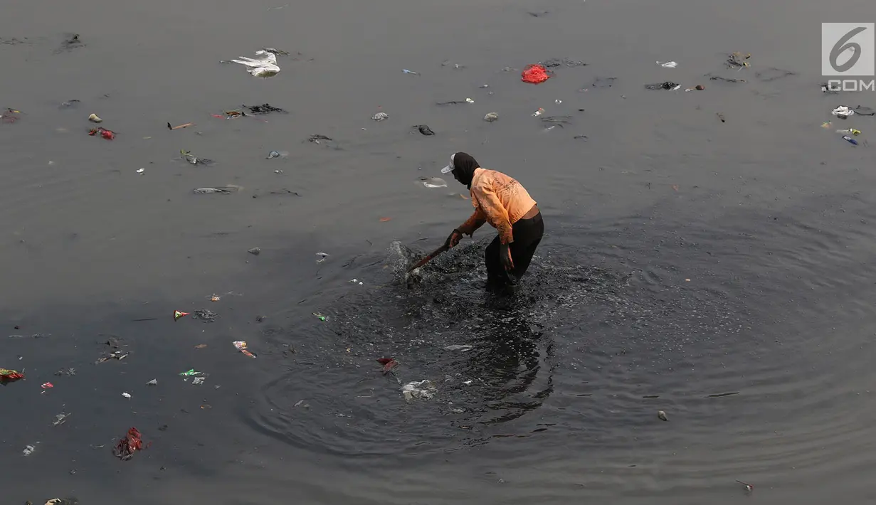 Petugas membersihkan sampah yang mengendap di Kanal Banjir Timur, Jakarta, Selasa (19/9). Diperkirakan sungai itu tercemar limbah sehingga airnya berwarna hitam pekat dan mengeluarkan bau tak sedap serta berbusa. (Liputan6.com/Immanuel Antonius)