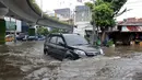 Sebuah mobil tampak nekat melintasi Jalan Matraman, Jakarta,  yang digenangi air, Sabtu (27/12/2014). (Liputan6.com/Miftahul Hayat)