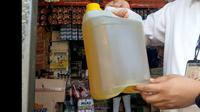 Salah satu petugas Polres Tasikmalaya, menujukan pasokan minyak goreng jenis curah di salah satu kios pasar tradisional Tasikmalaya, Senin (11/4/2022). (liputan6.com/Jayadi Supriadin)