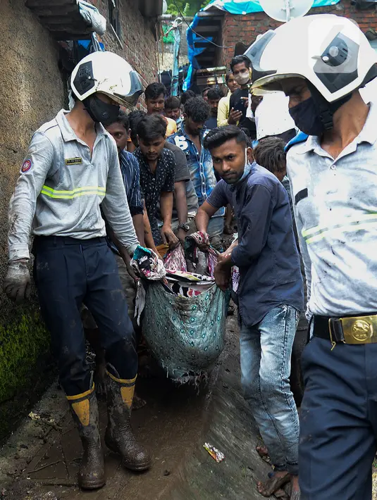 Tim penyelamat membawa jasad dari lokasi tanah longsor di daerah kumuh di Mumbai, India, Minggu (18/7/2021). Sebanyak 18 orang tewas setelah beberapa rumah hancur oleh dinding yang runtuh dan akibat tanah longsor yang dipicu oleh hujan lebat. (Sujit Jaiswal/AFP)