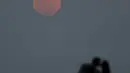 Sepasang kekasih berciuman dengan latar belakang fenomena alam Supermoon di Buenos Aires, Argentina, Minggu (27/9). Gerhana Bulan Supermoon (Bulan merah darah), kembali menampakkan keindahannya setelah 18 tahun tidak terjadi. (REUTERS/Enrique Marcarian)