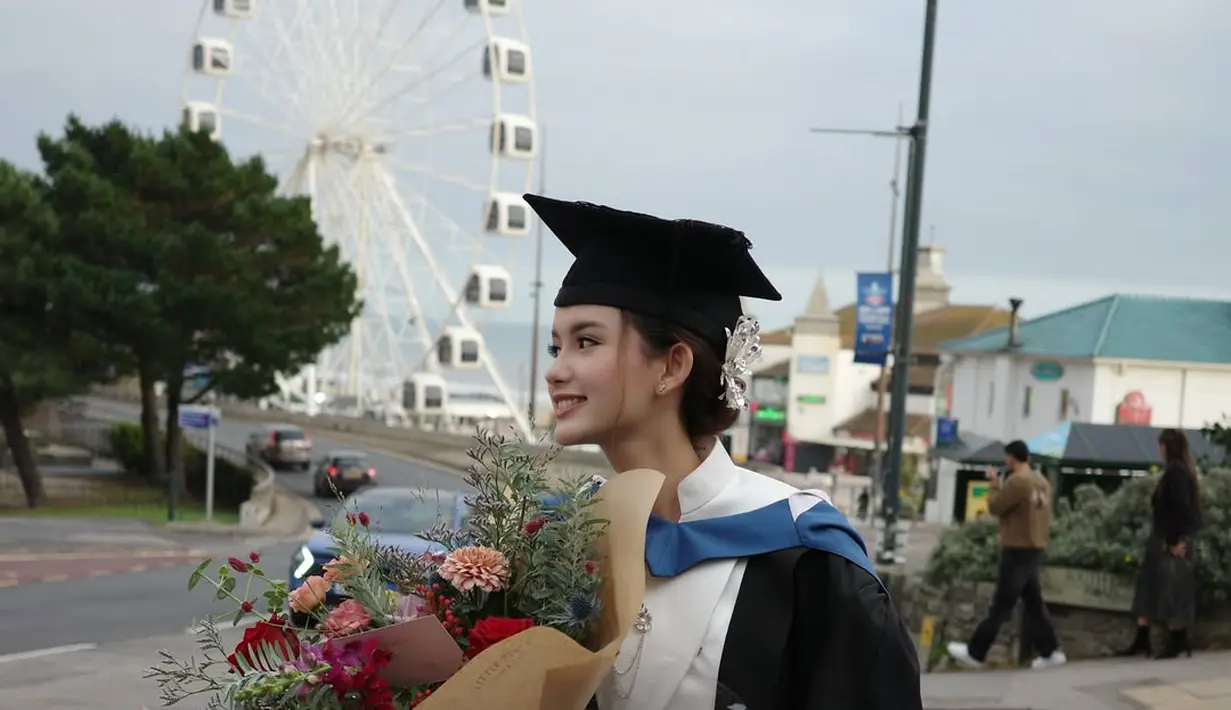 Rambut panjangnya ditata hairdo modern berhiaskan pita putih dan topi toga [@sarah_menzel]