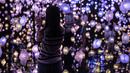 Seorang wanita mengambil foto "Pixel Forest" oleh seniman Swiss Pipilotti Rist, instalasi seni dari 3000 lampu LED pahatan tangan yang digantung di langit-langit di Tai Kwun di Hong Kong (18/8/2022). (AFP/Isaac Lawrence)