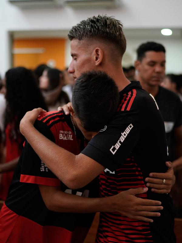 Pemain pemuda Flamengo Leoni Pereira (kiri) merangkul rekan setimnya dalam Misa peringatan untuk para korban kebakaran di akademi sepakbola Brasil, di Rio de Janeiro, Brasil (8/2). (AP Photo/Leo Correa)
