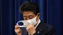 Perdana Menteri Jepang Shinzo Abe melepas maskernya saat konferensi pers di Kediaman Resmi Perdana Menteri, Tokyo, Jepang, Jumat (28/8/2020). Shinzo Abe pada 28 Agustus 2020 mengumumkan bahwa dia mengundurkan diri sebagai Perdana Menteri Jepang karena masalah kesehatan. (Franck ROBICHON/POOL/AFP)