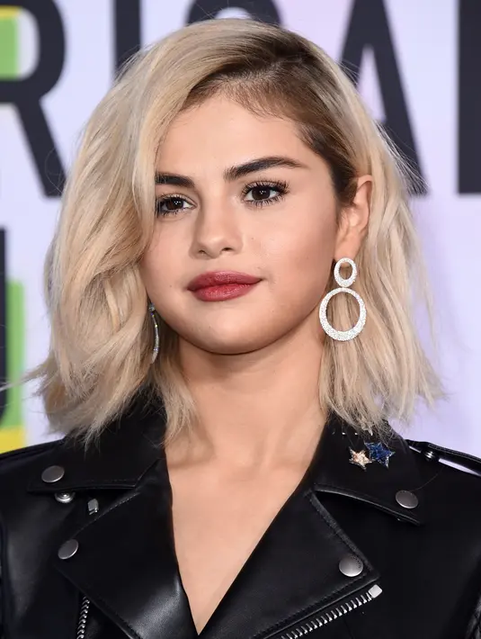 Penyanyi Selena Gomez berpose untuk fotografer di karpet merah American Music Awards 2017 di Microsoft Theatre, Los Angeles, Minggu (19/11). Wanita 25 tahun tersebut untuk pertama kalinya mencat rambutnya dengan warna pirang. (Jordan Strauss/Invision/AP)