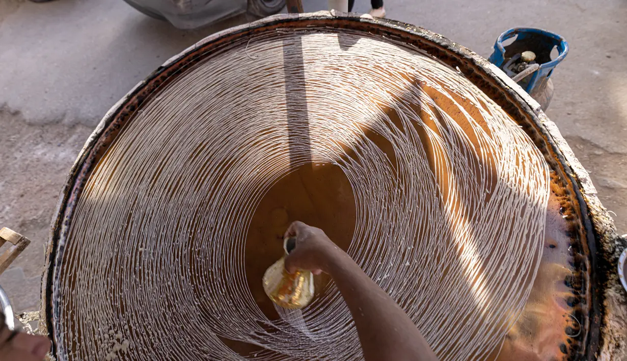 Pembuat penganan Mesir Mostafa Anwar membuat makanan penutup tradisional yang disebut "Kunafa" pada bulan Ramadhan, di kiosnya di ibu kota Kairo, 14 April 2022.  Kunafa terbuat dari adonan pastry mirip bihun, kemudian diisi dengan isian kacang, lalu dipanggang. (Khaled DESOUKI/AFP)