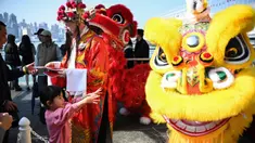 Seorang pria berpakaian seperti Cai Shen Ye atau Dewa Kekayaan Tionghoa membagikan dekorasi tradisional Fai Chun untuk keberuntungan dan kemakmuran di sebuah acara Tahun Baru Imlek di Hong Kong pada tanggal 10 Januari 2025. (Peter PARKS/AFP)