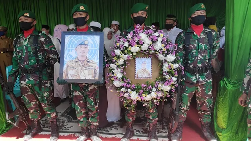 Prajurit TNI memegang foto dan karangan bunga di depan peti jenazah Pelda Anumerta Rama Wahyudi.