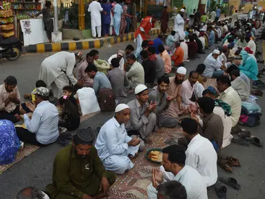 Muslim Pakistan berdoa sebelum berbuka puasa bersama di sepanjang jalan di Karachi pada 7 Mei 2019. Ketika bulan suci Ramadan mulai di Pakistan, banyak masyarakat muslim memanfaatkan buka puasa gratis yang disponsori oleh badan-badan amal dan orang-orang kaya. (RIZWAN TABASSUM / AFP)