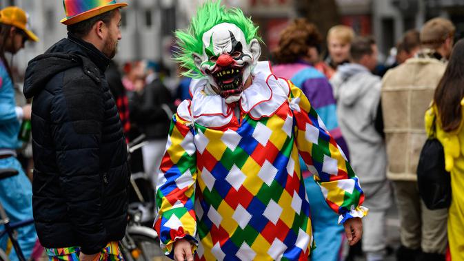 Seorang pria dengan mengenakan kostum Horror Clown berjalan saat puluhan ribu orang bersuka ria merayakan dimulainya musim karnaval di jalan-jalan Kota Cologne, Jerman, Senin (11/11/2019). Karnaval ini akan mencapai puncaknya pada bulan Februari 2020. (AP Photo/Martin Meissner)
