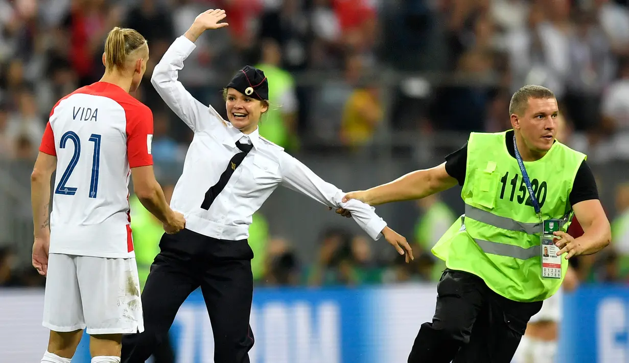 Petugas keamanan menarik penyusup wanita pada pertandingan sepak bola final Piala Dunia 2018, Prancis melawan Kroasia di Stadion Luzhniki, Moskow (15/7). Penyusup diketahui merupakan grup band punk Rusia, Pussy Riot.  (AP Photo / Martin Meissner)