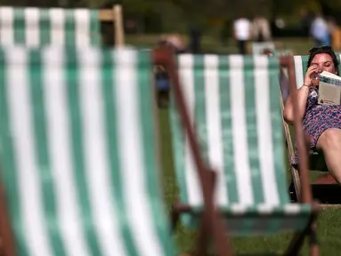 Seorang wanita membaca buku sambil menikmati sinar matahari di atas kursi di sebuah taman di London, Inggris, Rabu (4/5). Awal Mei, suhu udara hangat mulai menyelimuti kota London. (REUTERS/Neil Hall)