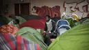 Para lelaki duduk di dekat tenda di sebuah gimnasium yang ditempati oleh para migran di lycee Jeanne-Bernard di Saint-Herblain, di luar Nantes, barat Prancis (28/3). Sekitar 250 imigran saat ini tinggal di tempat tersebut. (AFP Photo/Loic Venance)