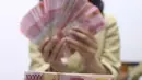 Pegawai menunjukkan mata uang rupiah di penukaran uang di Jakarta, Rabu (4/3/2020). Rupiah ditutup menguat 170 poin atau 1,19 persen menjadi Rp14.113 per dolar AS dibandingkan posisi hari sebelumnya Rp14.283 per dolar AS. (Liputan6.com/Angga Yuniar)