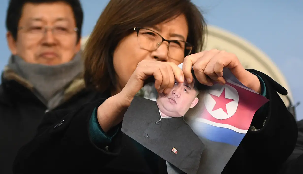 Seorang wanita yang membelot merobek foto pemimpin Korea Utara Kim Jong-Un saat konferensi pers di Majelis Nasional di Seoul (24/1). (AFP Photo/Jung Yeon-Je)
