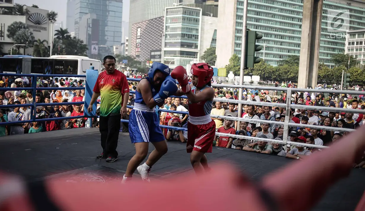 Dua petinju saling melepaskan pukulan pada pertandingan tinju amatir saat Car Free Day di kawasan Bundaran HI, Jakarta, Minggu (29/4). Kegiatan tinju yang diadakan di ruang terbuka tersebut menampilkan 30 partai amatir. (Liputan6.com/Faizal Fanani)