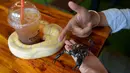 Foto pada 18 Agustus 2018 menunjukkan pelanggan bermain dengan ular piton dan kalajengking di Reptile Cafe, Phnom Penh, Kamboja. Sejauh ini bisnis kafe reptil itu masih berjalan merangkak karena rasa takut umum akan ular dan kadal. (AFP/TANG CHHIN Sothy)