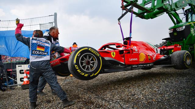 Petugas mengangkat mobil pebalap Jerman, Sebastian Vettel menggunakan traktor saat balapan F1 Grand Prix di Hockenheim racing circuit, Jerman, (22/7/2018). Vettel kehilangan kendali saat perubahan cuaca dan menabrak pembatas. (AFP/Andrej Isakovic)