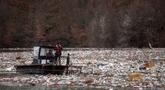 Pekerja perusahaan utilitas mendorong limbah ke tepi Sungai Lim dekat Priboj, Serbia, 30 Januari 2023. Botol plastik, papan kayu, tong berkarat, dan sampah lainnya dari tempat pembuangan sampah tepi sungai yang tidak diatur dengan baik terakumulasi selama air pasang. (AP Photo/Armin Durgut)