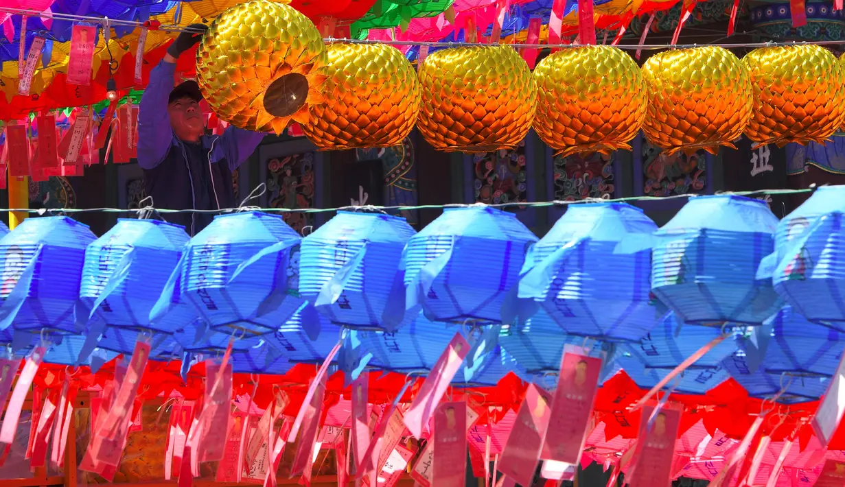 Pekerja memasang lampion di Jogye Temple jelang perayaan ulang tahun Buddha, Seoul, Rabu (12/4). Di Negeri Ginseng ini, ulang tahun Buddha dirayakan dengan menggelar ‘Lotus Lantern Festival’. (AFP PHOTO / JUNG Yeon-Je) 