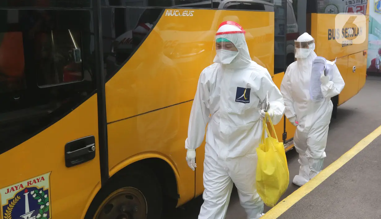 Petugas medis berjalan memasuki bus sekolah di Puskesmas Kecamatan Ciracas, Jakarta, Kamis (10/06/2021). Kasus positif di Jakarta bertambah 2.096 orang, sehingga total kasus positif bertambah menjadi 440.554 orang. (Liputan6.com/Herman Zakharia)