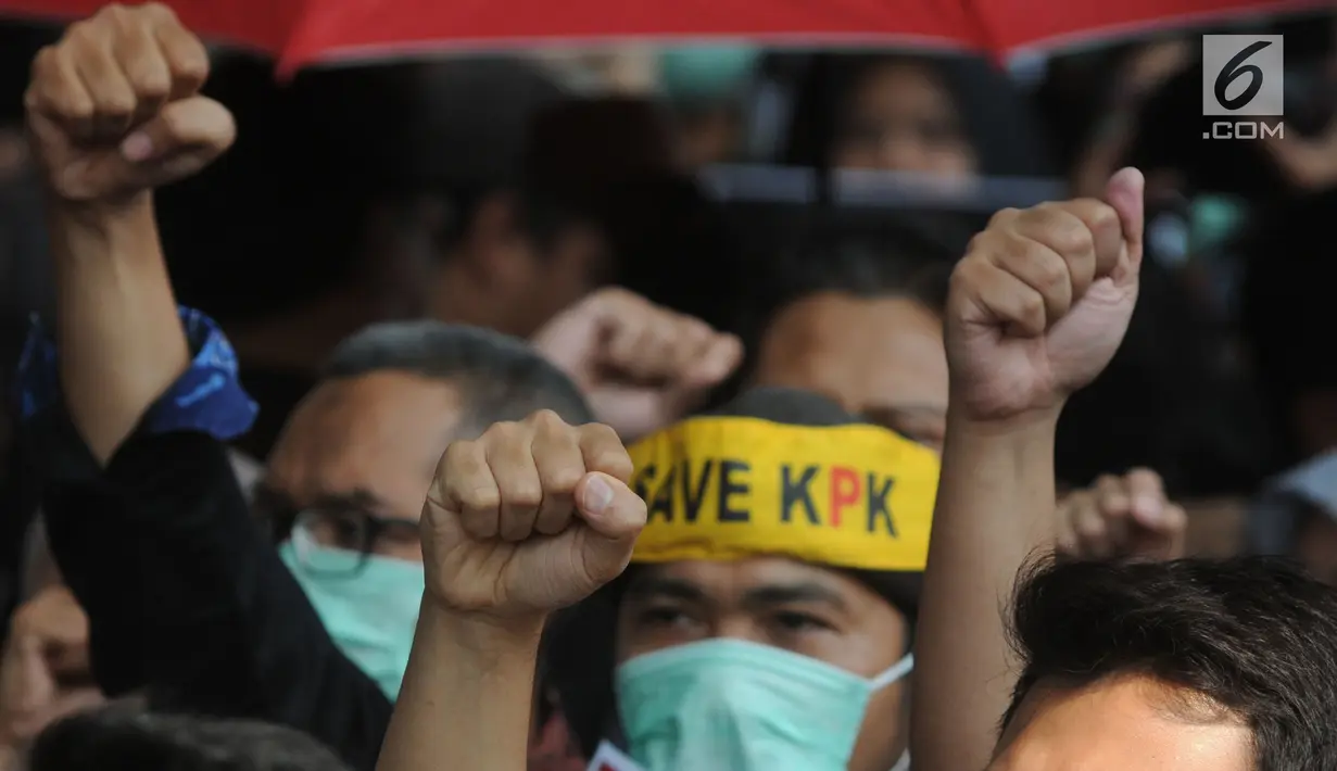 Pegawai KPK membawa poster saat menggelar aksi di Lobi Gedung KPK, Kuningan, Jakarta, Jumat (6/9/2019). Dalam aksi menolak revisi UU KPK tersebut, mereka mengenakan baju serba hitam lengkap dengan masker penutup mulut dan membawa payung. (merdeka.com/Dwi Narwoko)