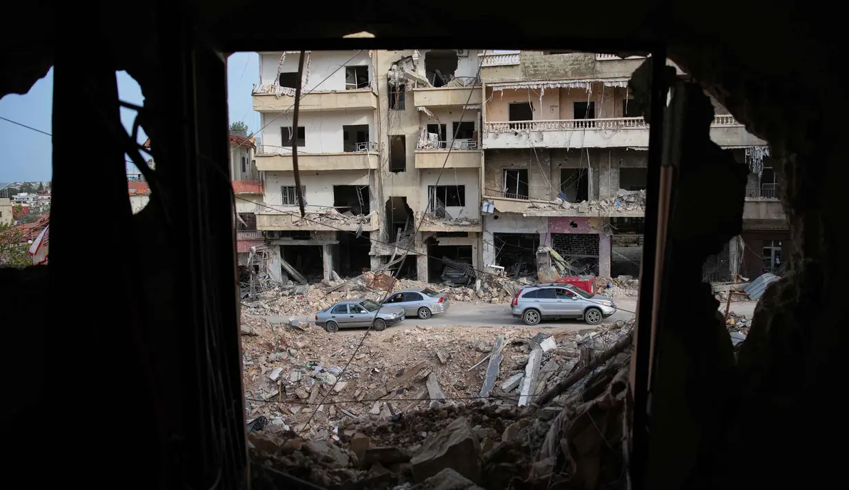 Kementerian Kesehatan Lebanon mencatat hingga Jumat 10 April 2026, secara keseluruhan 1.953 orang tewas dan 6.303 lainnya terluka sejak perang meletus antara Israel dan Hizbullah pada 2 Maret 2026. Tampak dalam foto, warga setempat melintas di lokasi bangunan yang hancur akibat serangan udara Israel, di Jibchit, Lebanon Selatan, Jumat, 17 April 2026, setelah gencatan senjata antara Israel dan Hizbullah. (AP Photo/Hassan Ammar)