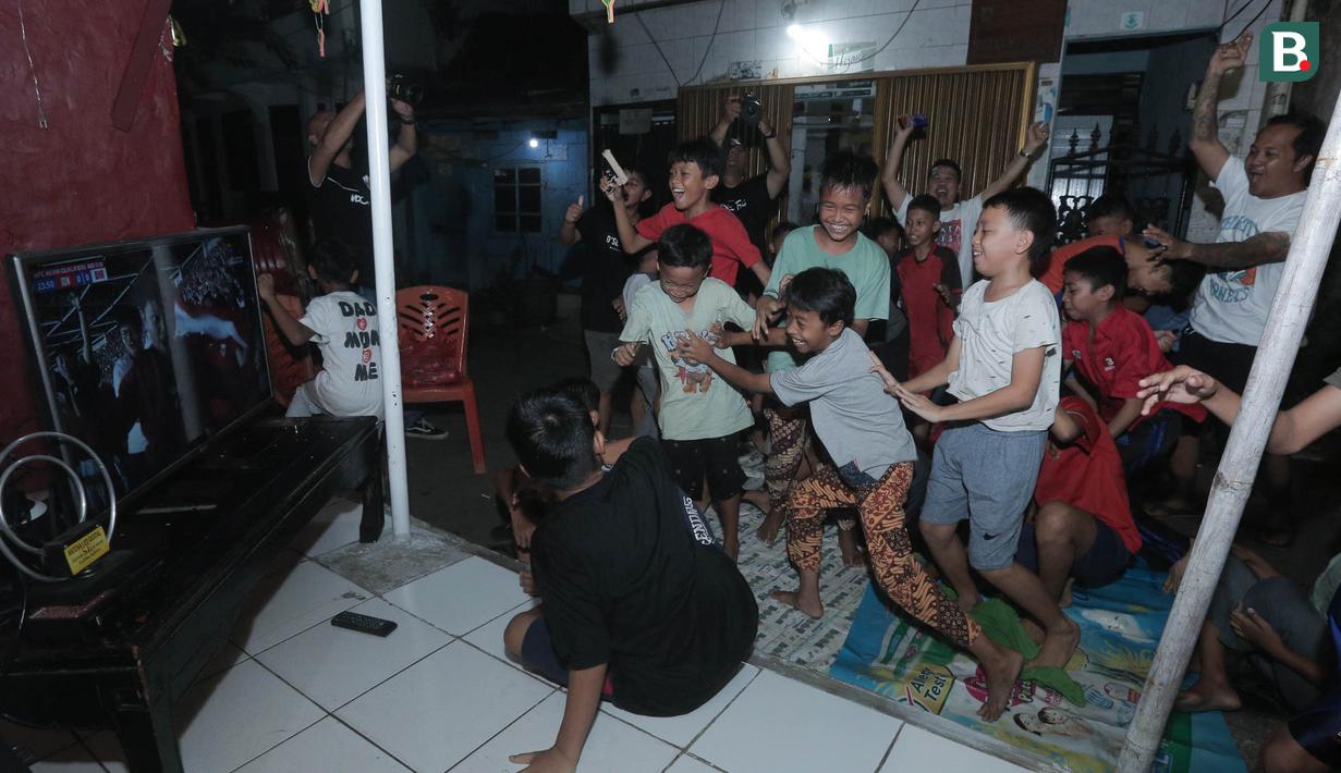 Sejumlah warga merayakan gol yang dicetak oleh Ole Romeny ke gawang Bahrain dalam pertandingan Grup C putaran ketiga Kualifikasi Piala Dunia 2026 zona Asia di kawasan Menteng Jaya, Jakarta, Selasa (25/5/2025). (Bola.com/M Iqbal Ichsan)