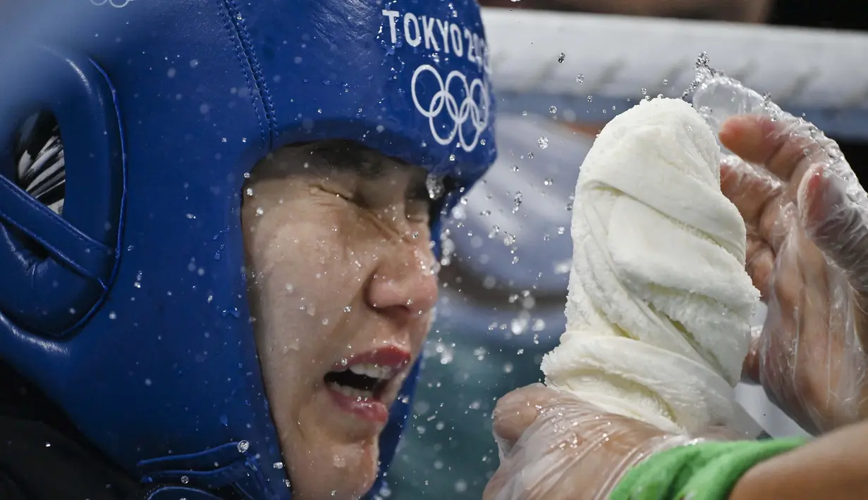 Pelatih memercikkan air ke wajah petinju asal Uzbekistan, Tursunoy Rakhimova dalam pertandingan tinju kelas terbang putri pada Olimpiade Tokyo 2020, Kamis (29/7/2021). (Foto: AP/Pool/Luis Robayo)