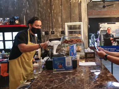 Artis sekaligus pemilik Unfinished Coffee Mario Lawalata (kiri) saat melayani CEO PT Sprint Asia Technology Setyo Harsoyo (Bayarind) di Unfinished Coffee, Jakarta (18/02/2021). Tiga tahun beroperasi, Bayarind menyediakan layanan transaksi digital yang aman dan bersahabat. (Liputan6.com/Fery Pradolo)