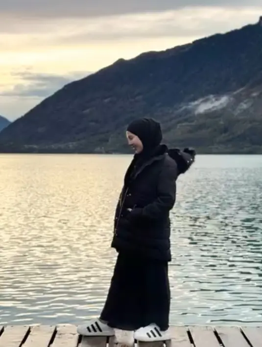 Ratna Galih juga mengenakan tampilan serba hitam saat berada di Swiss. Ia memadukan long padding jaket dengan rok skirt dan sepatu Adidasnya. [@ratnagalih]