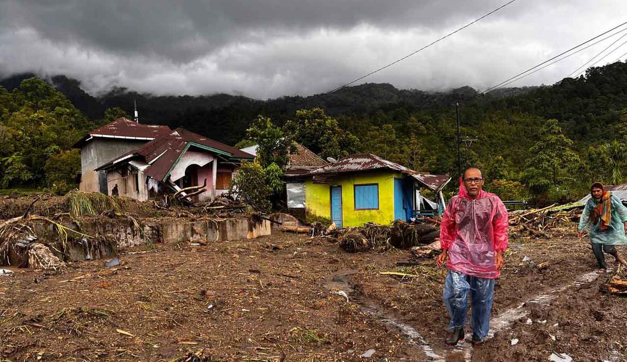 Warga berjalan melewati rumah-rumah yang rusak di sebuah desa yang terdampak banjir di Malalak, Sumatera Barat, Jumat 28 November 2025. Jelang akhir November 2025, bencana banjir bandang dan tanah longsor melanda sebagian besar wilayah pulau Sumatera. (AP Photo/Ade Yuandha)