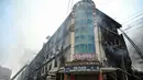 Petugas pemadam kebakaran dan tim SAR masih menyisir area gedung untuk memastikan tidak ada korban yang terjebak di bawah puing-puing. Tampak dalam foto, petugas pemadam kebakaran dan tim penyelamat melakukan operasi pendinginan di tengah puing-puing setelah kebakaran besar di sebuah pusat perbelanjaan di Karachi pada Senin 19 Januari 2026. (Asif HASSAN/AFP)