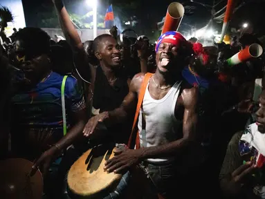 Warga Haiti turun ke jalan-jalan di Port-au-Prince saat merayakan lolosnya tim nasional mereka di putaran final Piala Dunia 2026, pada Selasa 18 November 2025 waktu setempat. Timnas Haiti memastikan lolos ke Piala Dunia 2026 usai mengalahkan Nikaragua dengan skor 2-0. (Clarens SIFFROY/AFP)