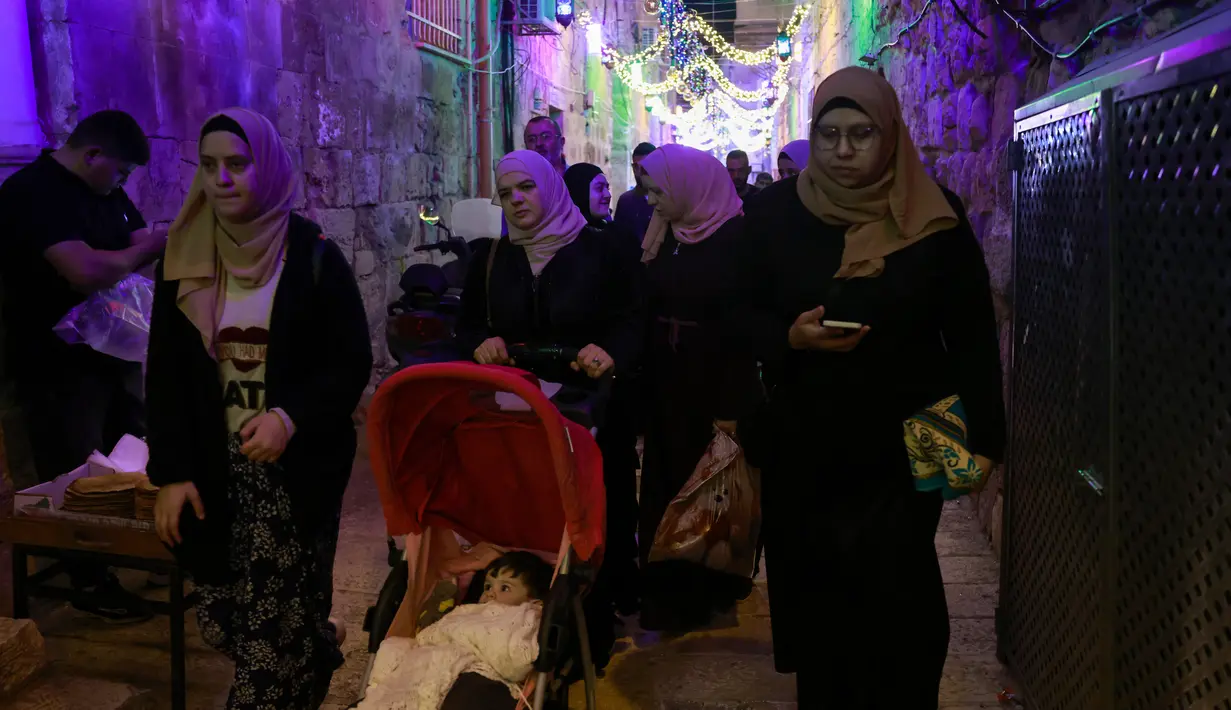 Warga Palestina berjalan menyusuri jalan pada hari pertama bulan suci Ramadhan di Kota Tua Yerusalem, 2 April 2022. Ramadan adalah bulan suci umat Islam yang dirayakan dengan cara melaksanakan puasa selama satu bulan penuh. (Menahem KAHANA / AFP)