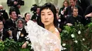 Greta Lee mengenakan gaun putih Loewe dengan hiasan bunga. Gaun tersebut tampak transparan. [@loewe]