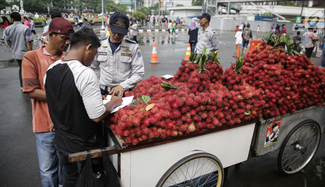 Pedagang mengisi surat pernyataan saat ditindak oleh Petugas Dinas Perhubungan di CFD di kawasan Bunderan HI, Jakarta, Minggu (4/2). Penindakan ini dilakukan agar kawasan CFD tertib dan rapih dari pedagang. (Liputan6.com/Faizal Fanani)