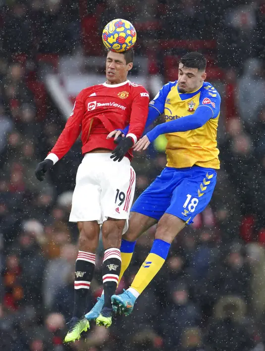 Pemain Manchester United Raphael Varane (kiri) berebut bola dengan pemain Manchester United Bruno Fernandes pada pertandingan sepak bola Liga Inggris di Stadion Old Trafford, Manchester, Inggris, 12 Februari 2022. Pertandingan berakhir dengan skor 1-1. (AP Photo/Jon Super)