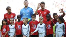 Pemain Bayern Muenchen Philipp Lahm, Manuel Neuer dan Thomas Mueller berfoto dengan anak-anak pengungsi (kaos merah) sebelum melawan FC Augsburg dalam lanjutan Liga Jerman. Sabtu (12/9/2015). (AFP Photo/DPA/Anandreas Gebert)