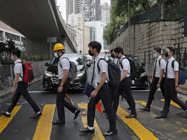 Para siswa sekolah mengenakan topeng dan helm berjalan di luar St. Paul's College selama protes di Hong Kong, Selasa (3/9/2019). Puluhan ribu siswa di Hong Kong mogok sekolah di hari pertama tahun ajaran baru. (AP Photo/Kin Cheung)