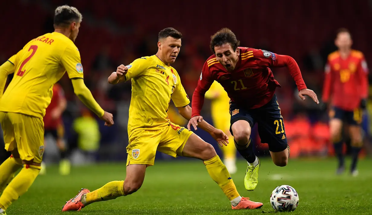 Pemain timnas Spanyol Iquel Oyarzabal terjatuh ketika berebut bola dengan bek Rumania Adrian Rus pada matchday ke-10 Grup F Kualifikasi Piala Eropa 2020 di Wanda Metropolitano, Senin (18/11/2019). Spanyol berhasil menggasak Rumania 5-0. (PIERRE-PHILIPPE MARCOU / AFP)