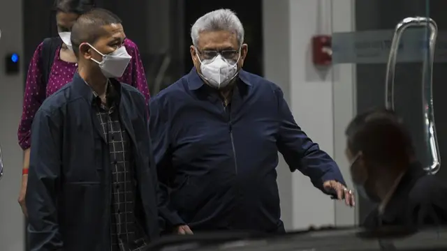 Mantan Presiden Sri Lanka Gotabaya Rajapaksa (tengah) berjalan ke kendaraan yang menunggu di luar bandara Don Mueaung di Bangkok, Thailand Kamis, 11 Agustus 2022. (AP Photo/Tananchai Keawsowattana)